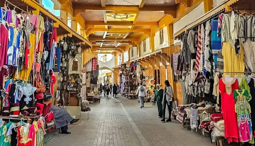 This image captures the vibrant scene of an old market in Rabat, likely showcasing traditional Moroccan goods, such as clothing, lamps, and crafts.