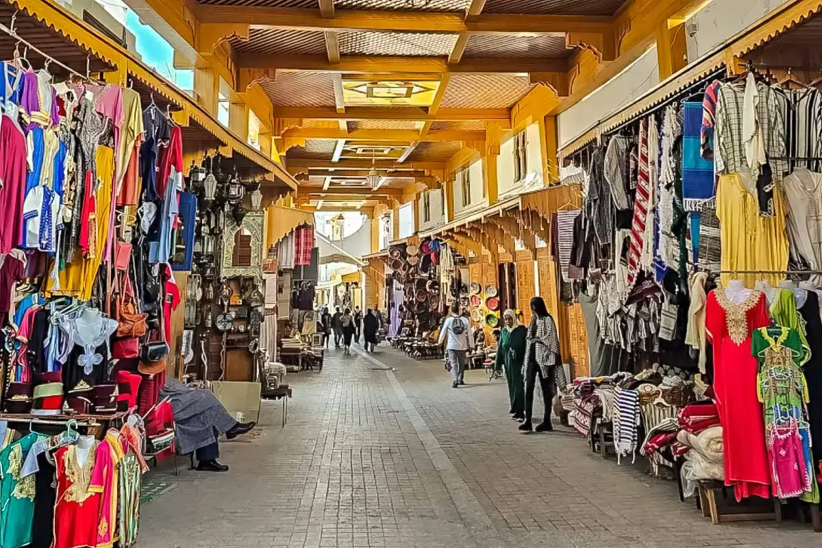 This image captures the vibrant scene of an old market in Rabat, likely showcasing traditional Moroccan goods, such as clothing, lamps, and crafts.