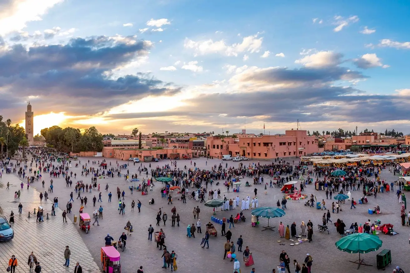 a crowd of people standing around a parking lot in marrakech