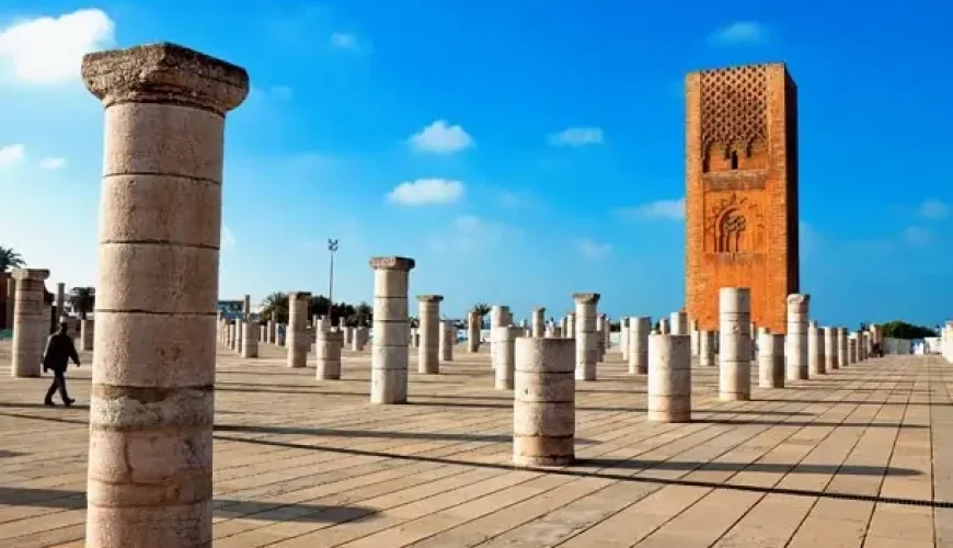 Another view of the Hassan Tower, beautifully lit up at dusk with the reflection on the water, highlighting the serene atmosphere around the monument.