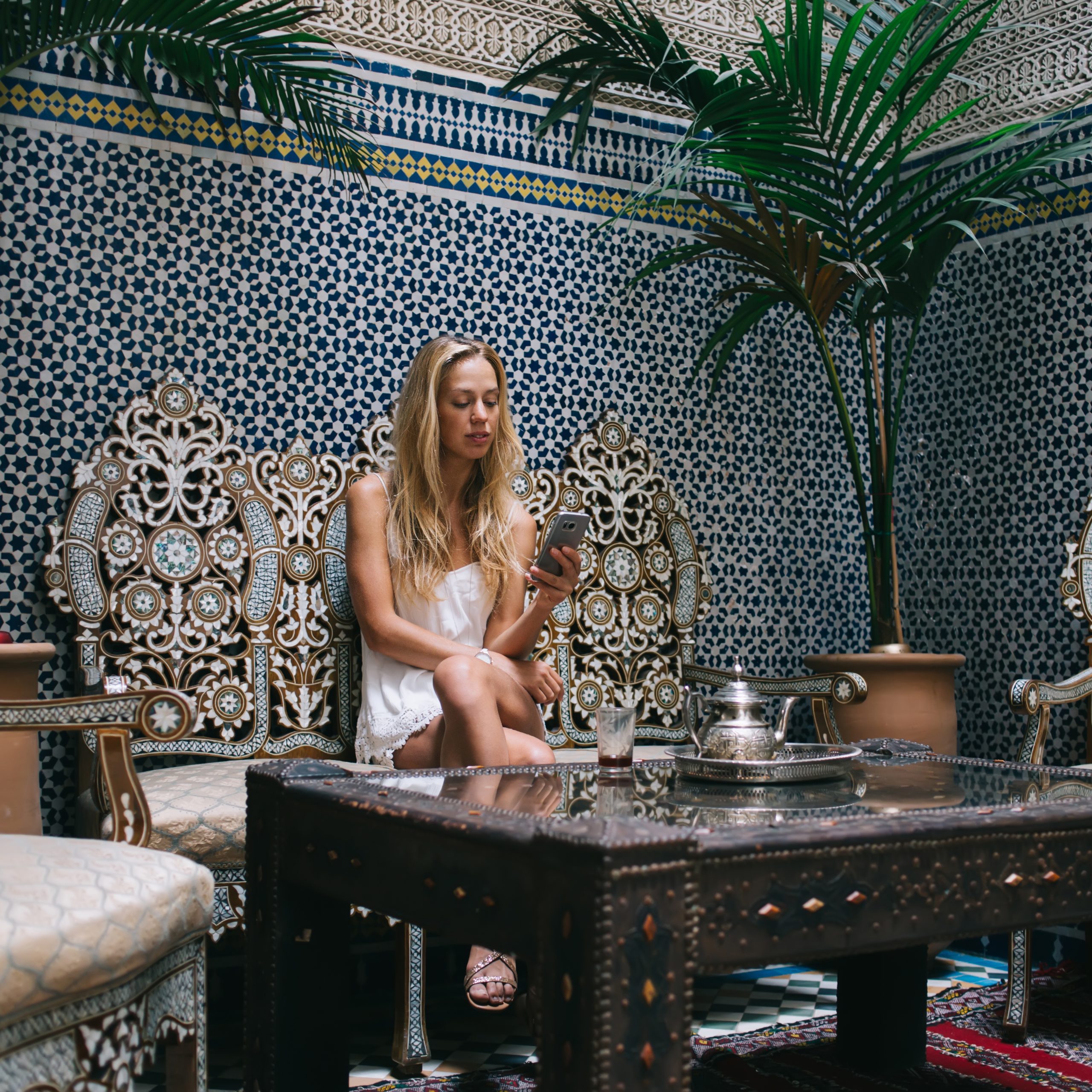 Peaceful attractive female with crossed legs in casual clothes watching cellphone surfing social media having cup of tea spending time in cafe of Morocco 12 days from casablanca