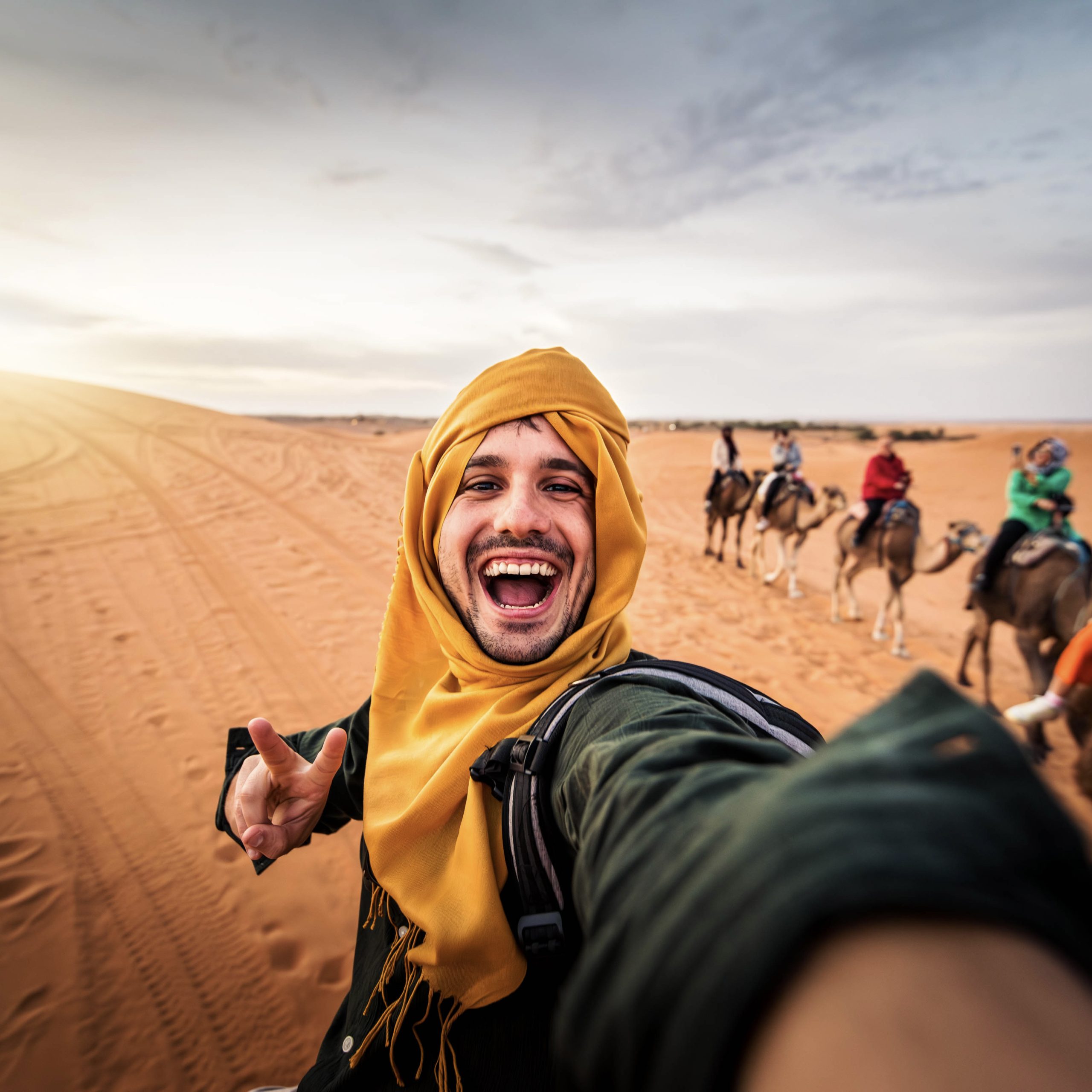 Happy tourist having fun enjoying group camel ride tour in the desert - Travel, life style, vacation activities and adventure concept