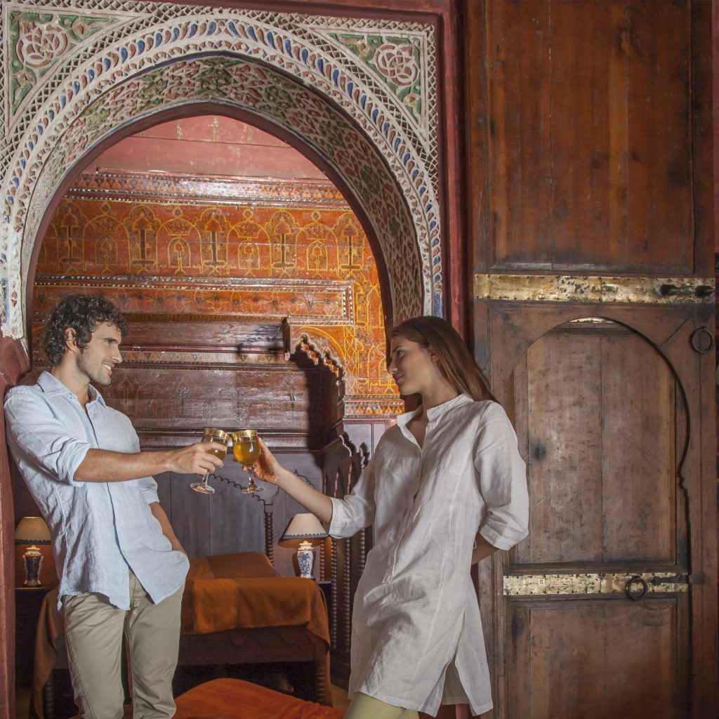 Young couple in riad making a toast in archway, Marrakesh, Morocco
